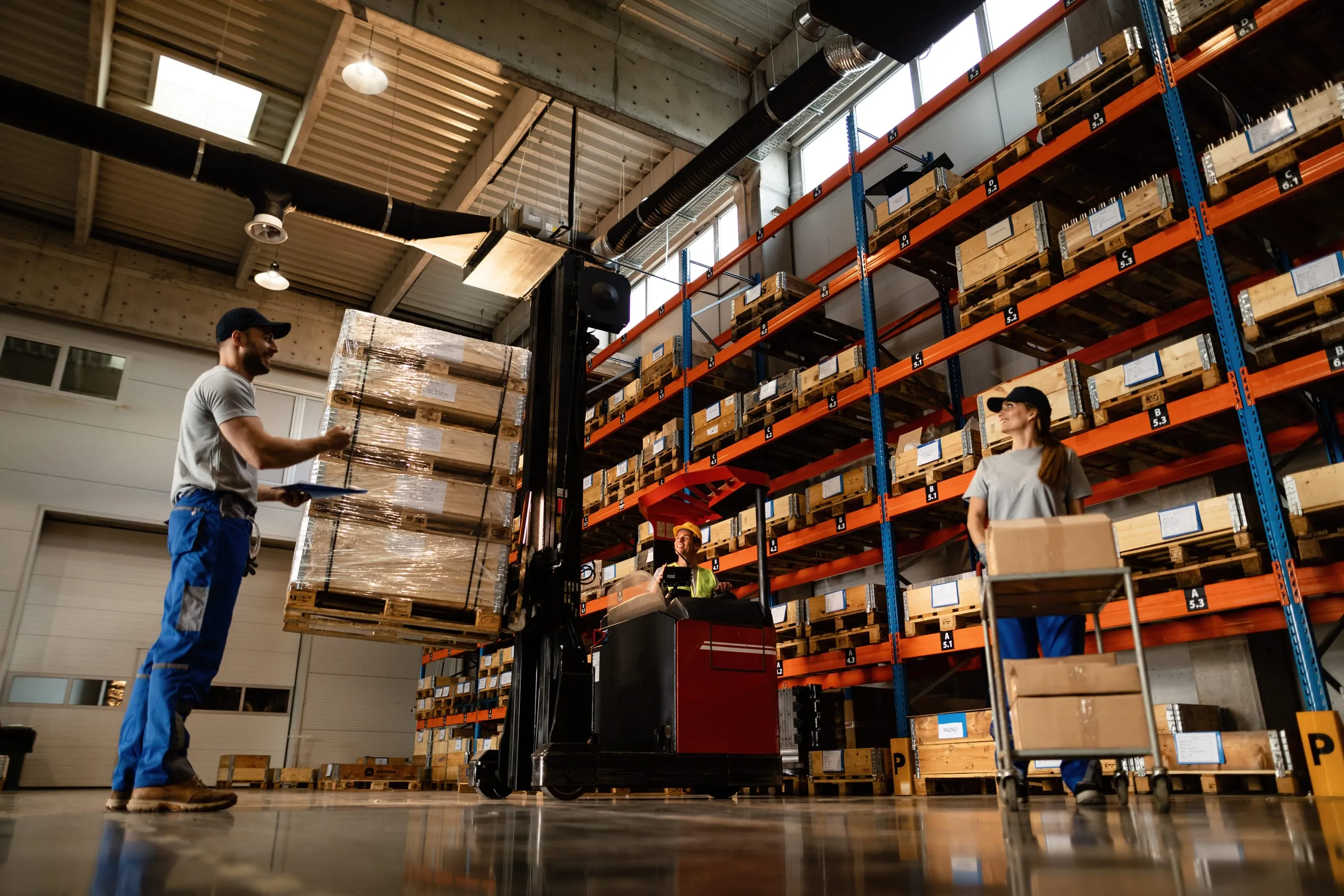 Operadores y montacargas trabajando entre racks industriales