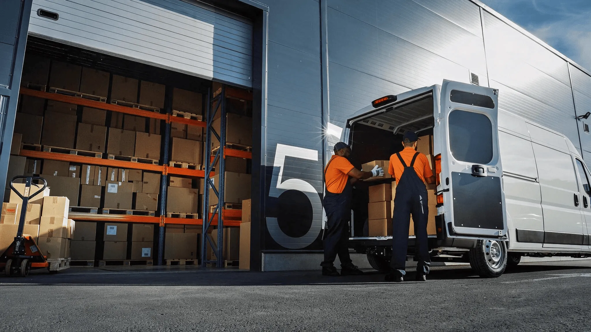 Dos operadores cargando cajas en una camioneta de reparto en el andén